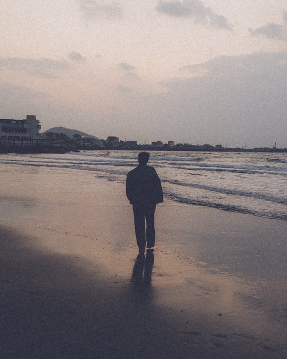 Walking alone along the shore as dusk turns blue