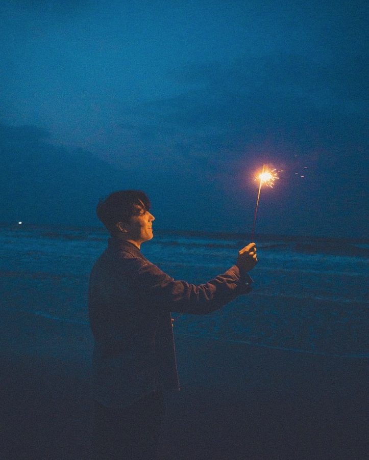 Holding a sparkler against the dark sea