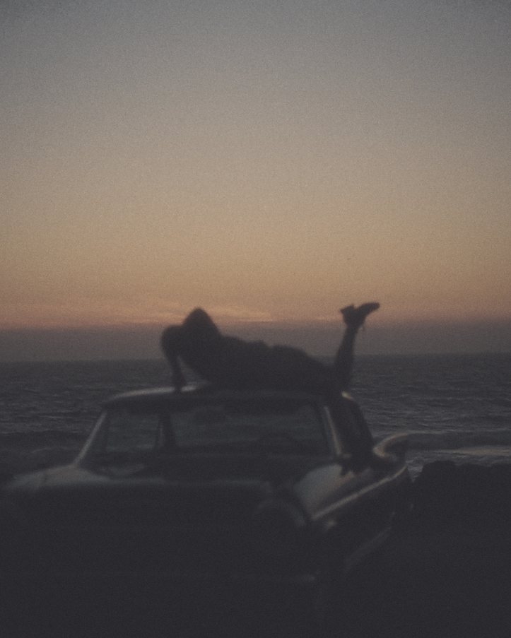 Lying on the hood of a car as the sky fades