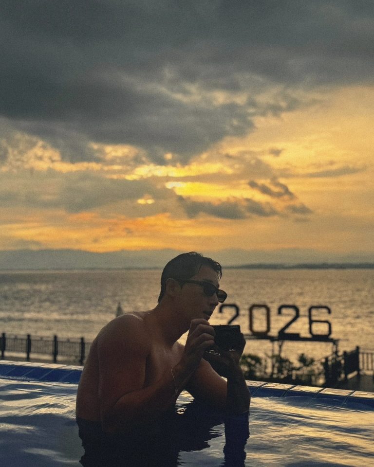 Holding a camera in the pool under a golden sky